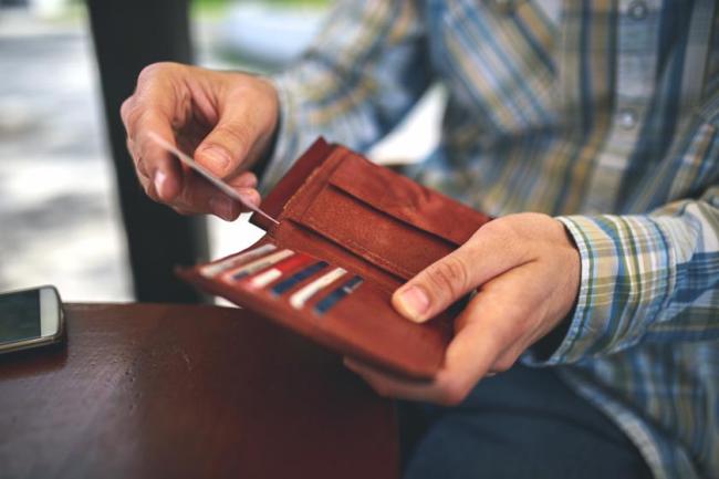 Man in a plaid shirt taking a card out of his wallet at the counter.