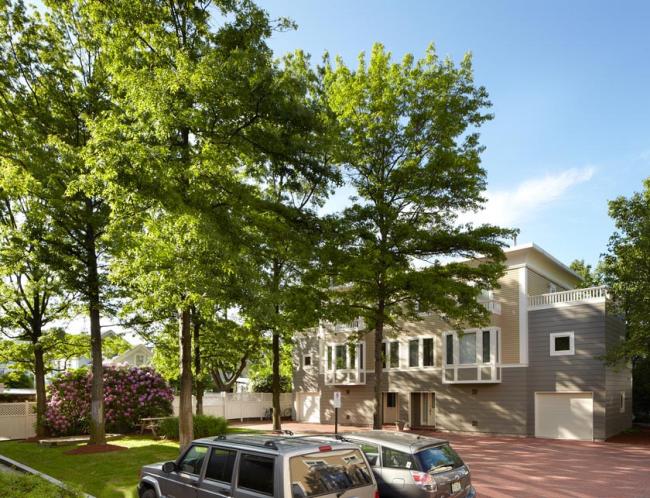 A street view of the Observatory Commons condominium property, lined with tall green trees.  