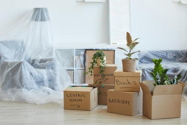 Six labeled cardboard boxes on the floor of a new home ready to be unpacked