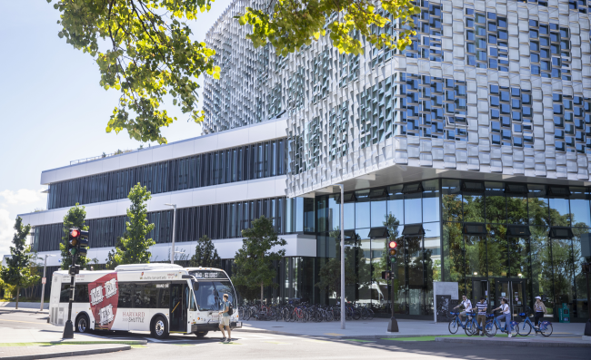 A photo of a Harvard University bus in front of the Harvard SEAS building