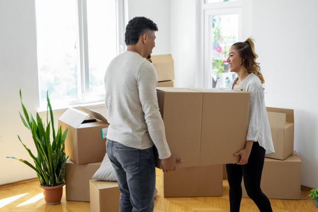 two people moving a large cardboard box together
