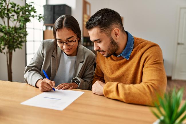 two people signing a document together