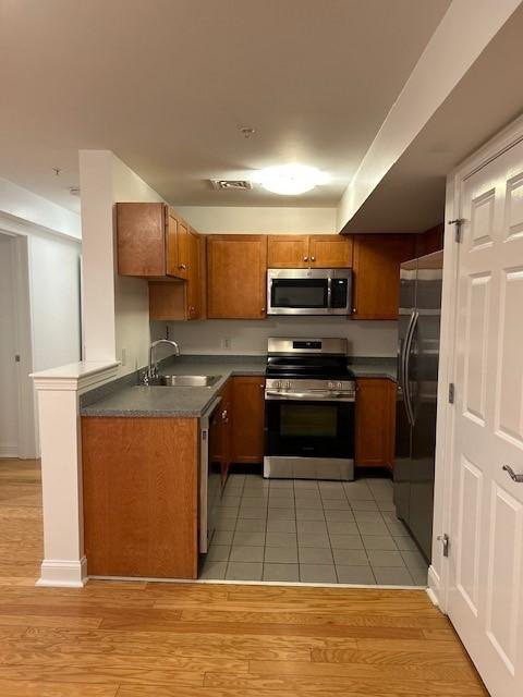 kitchen with grey countertops, tiled flooring, and wood cabinetry with stainless steel appliances