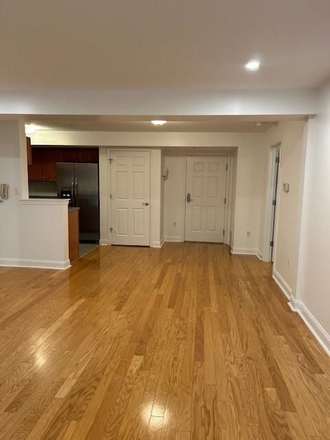 Living and dining room view with hardwood flooring and overhead lighting, view is facing the kitchen.