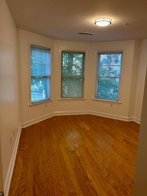 Second bedroom with hardwood flooring, bay windows, white walls, and overhead lighting