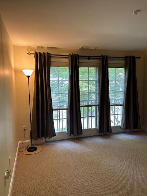 a large room with floor to ceiling windows, dark curtains, and a floor lamp in the corner.Room is carpeted.