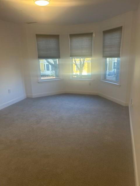 Bedroom with bay windows, overhead lighting, neutral colored carpet, and white walls