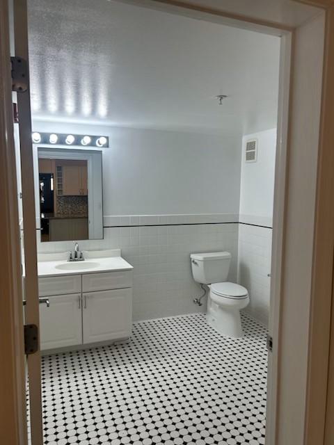 Secondary bathroom with black and white tiling, toilet, vanity, sink