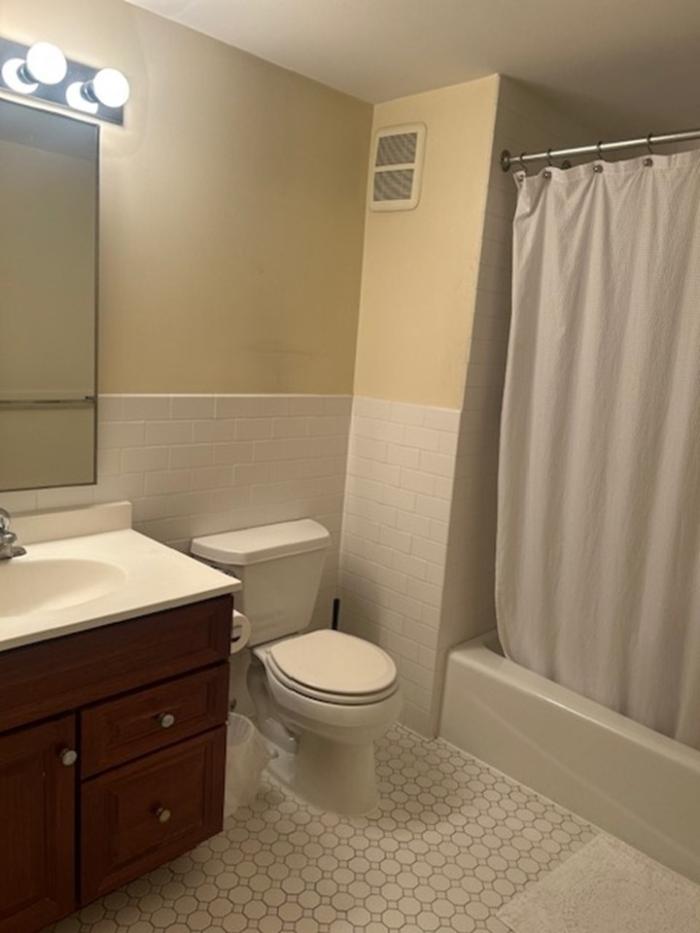 Bathroom with a tub/shower, toilet, and sink/vanity. Tile flooring.