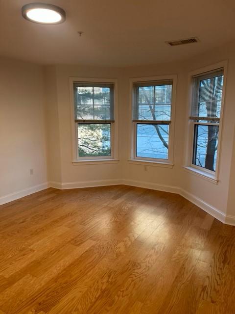 Secondary bedroom with hard flooring, overhead lighting, and bay windows