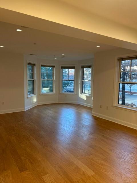 Open concept living and dining area with bay windows and hard flooring, recessed lighting