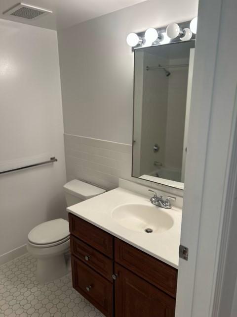 Primary bathroom with toilet, sink, vanity, and white tiling