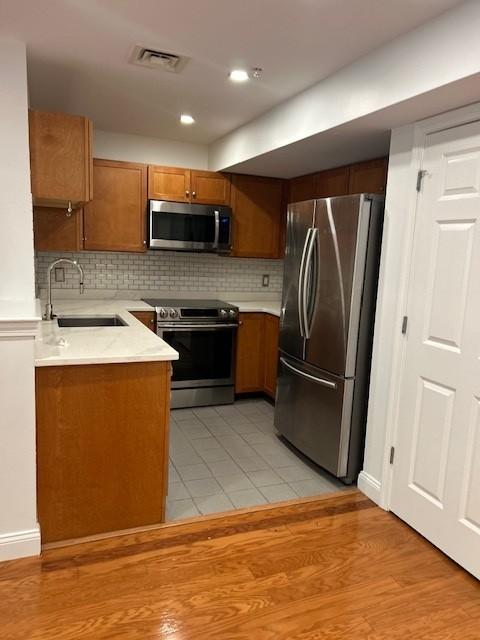 kitchen with stainless steel appliances, oak cabinets, white countertops, and white tile flooring