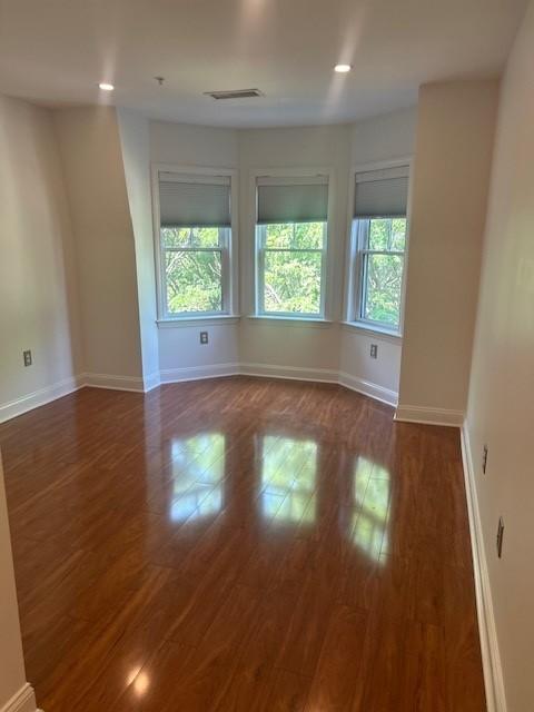primary bedroom with hard flooring, recessed lighting, and large bay windows