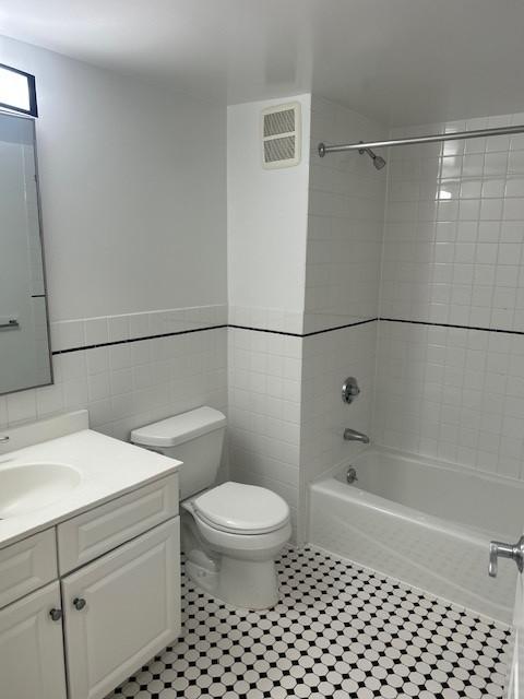 Secondary bathroom with tile flooring, white toilet, shower/tub, sink and vanity