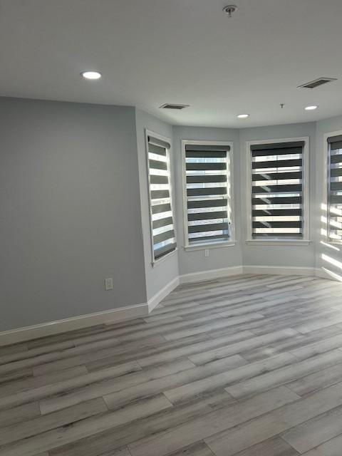Primary bedroom with bay windows and hard flooring, recessed lighting