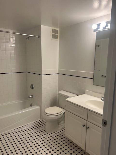 second bathroom with tile flooring, tub/shower combo, toilet, and sinky vanity with cabinet storage