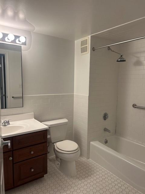 Primary bathroom with tile flooring, tub/shower combo, toilet, and sinky vanity with cabinet storage
