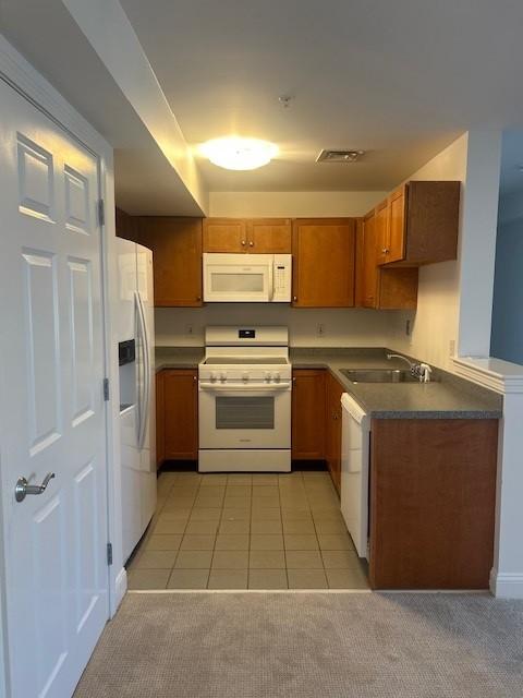 kitchen with overhead lighting, tile flooring, dark wood cabinets, grey countertops, and white appliances