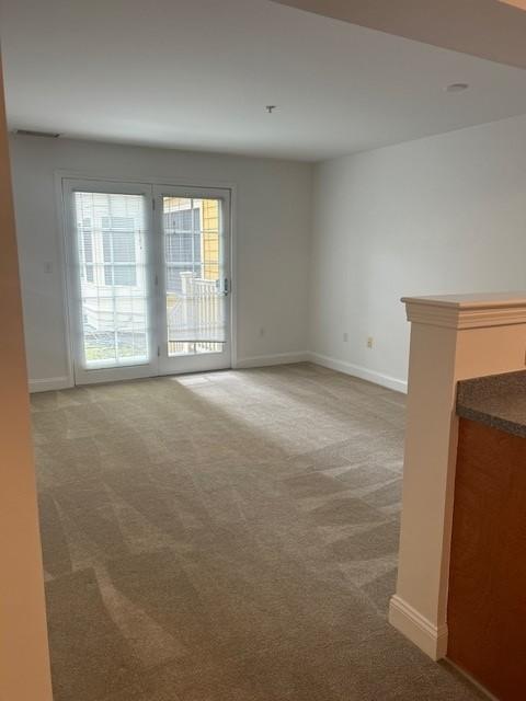 Combined living and dining area with carpeting and large windows
