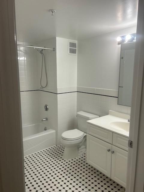 Secondary bathroom with toilet, tile flooring, tub, and vanity