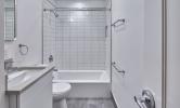 a sample bathroom in 13 Kirkland with hard flooring, white tiled shower/tub, vanity, and toilet