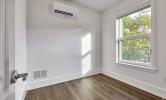 a sample bedroom in 5 Sacramento with the mounted HVAC unit and hardwood floors