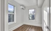 a sample bedroom in 5 Sacramento with the mounted HVAC unit and hardwood floors. 