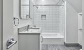 a sample bathroom in 5 Sacramento with white tiled shower/tub, vanity, and toilet