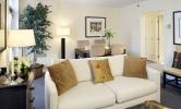 A warm and inviting living room with couch in the foreground and table and chairs in the background.