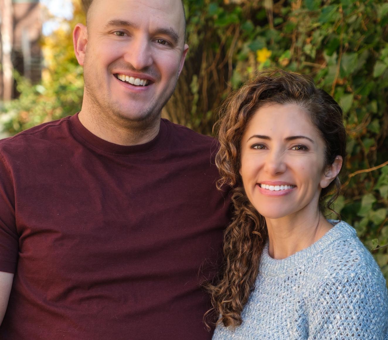 Todd and Sara posing together outside on a sunny day, smiling at the camera.